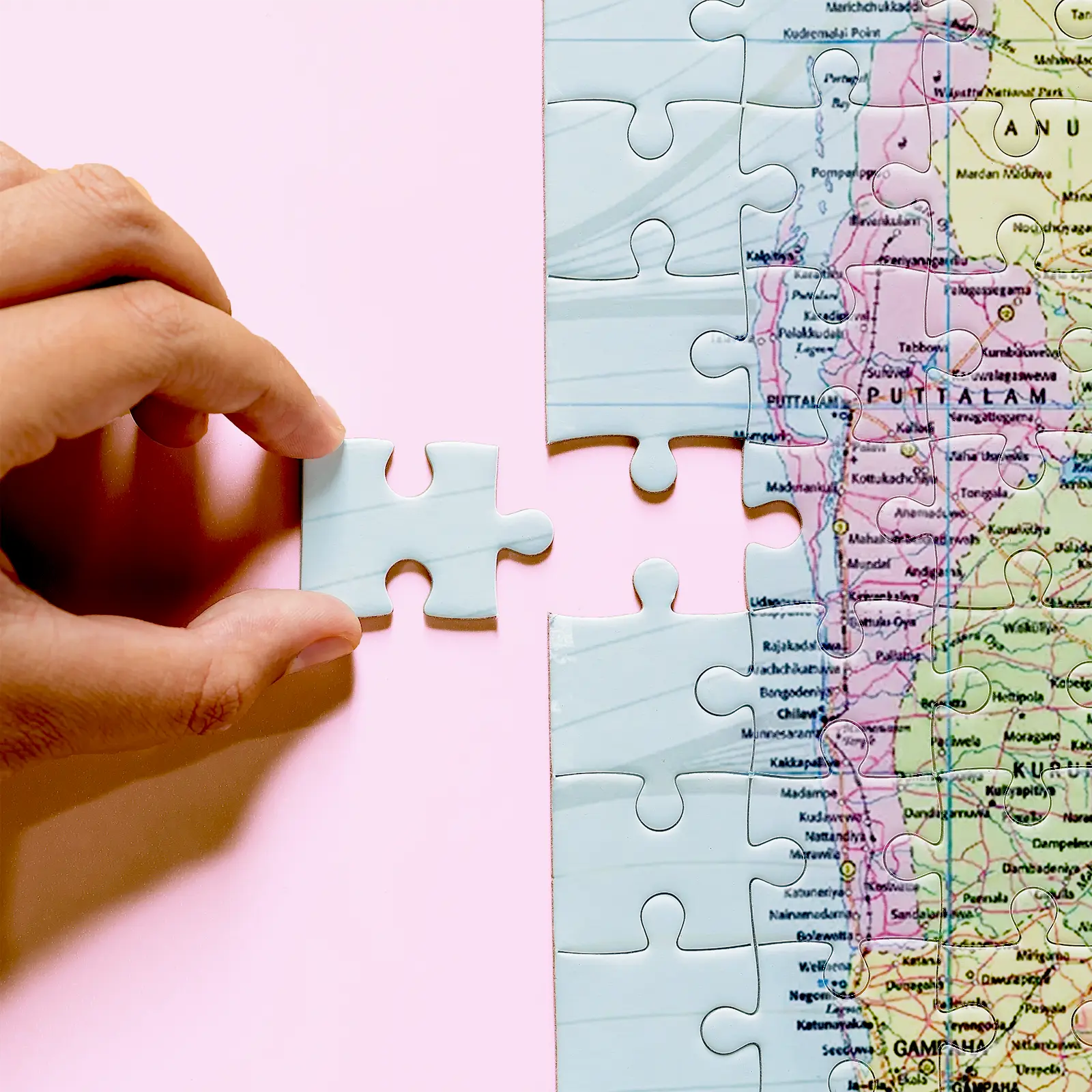 Hand holding a pale blue puzzle piece beside the Sri Lanka map near Puttalam